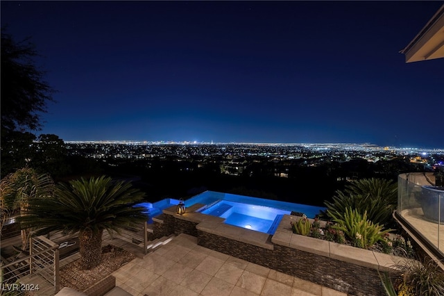 pool at twilight with an in ground hot tub and a patio