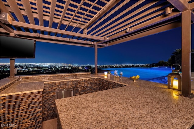 patio at night featuring a water view