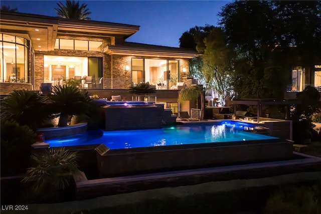 pool at twilight featuring an in ground hot tub