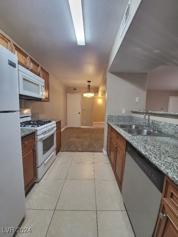 kitchen featuring white appliances, light stone countertops, sink, a textured ceiling, and light tile patterned floors