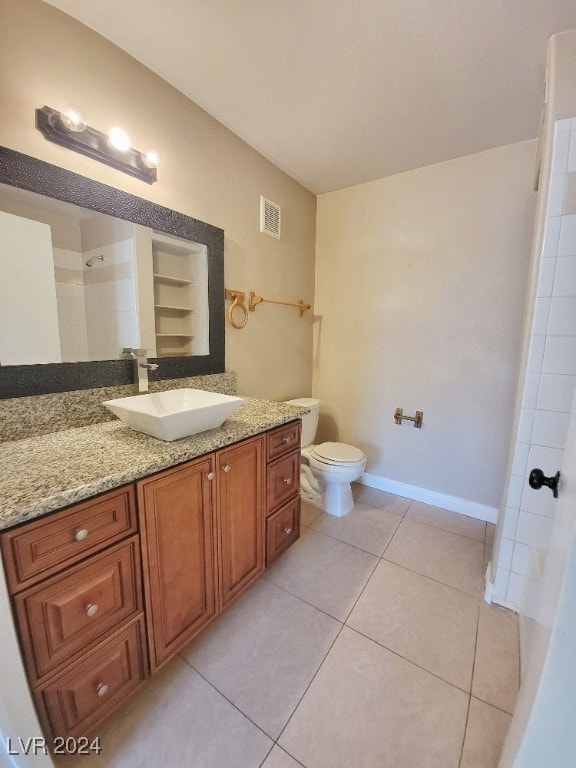 bathroom with toilet, vanity, and tile patterned flooring