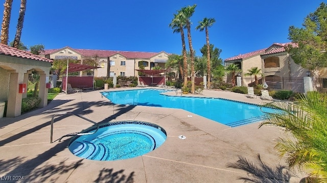 view of swimming pool featuring a community hot tub and a patio area