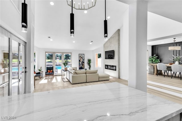 living room featuring french doors, high vaulted ceiling, and an inviting chandelier