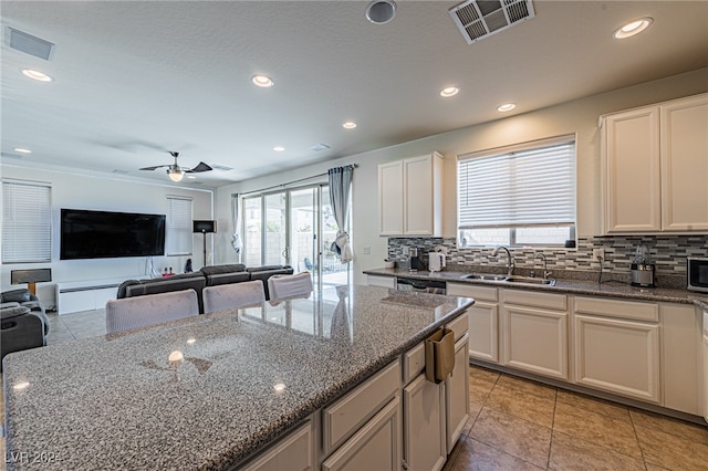 kitchen with dark stone counters, sink, and plenty of natural light