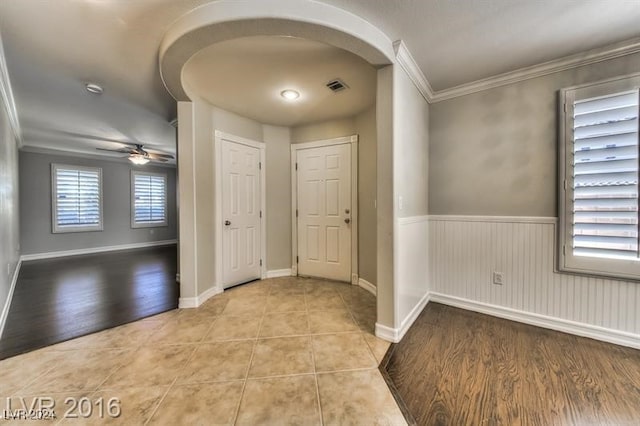 foyer entrance with crown molding, light wood-type flooring, and ceiling fan