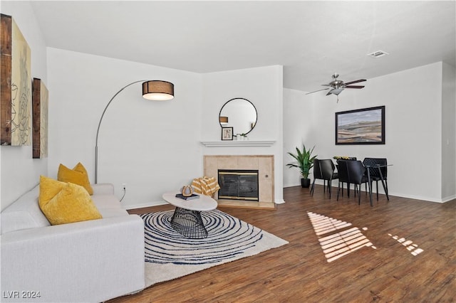 living room with a fireplace, dark wood-type flooring, and ceiling fan