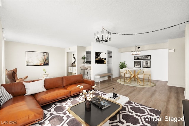 living room with hardwood / wood-style flooring, a chandelier, and a textured ceiling