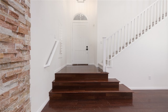 stairway featuring a towering ceiling and wood-type flooring