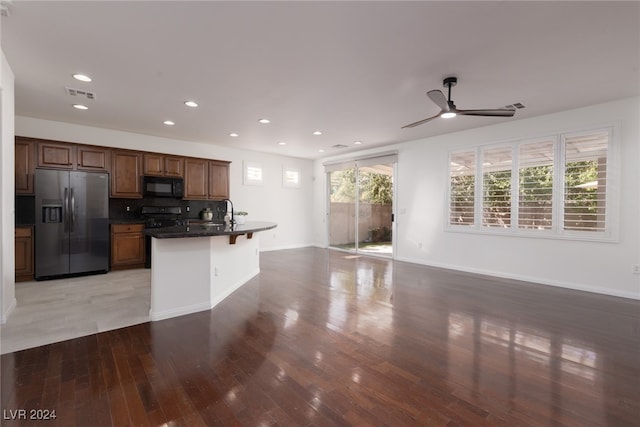 kitchen with light hardwood / wood-style flooring, black appliances, plenty of natural light, and backsplash