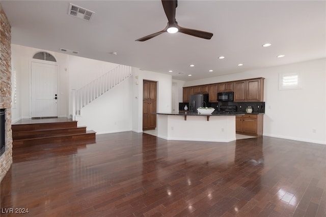 kitchen featuring dark wood-type flooring, stainless steel fridge with ice dispenser, a kitchen bar, and tasteful backsplash