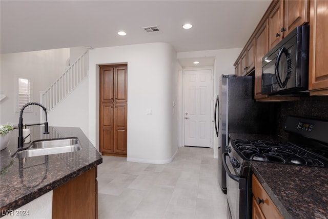 kitchen featuring black appliances, sink, and dark stone counters