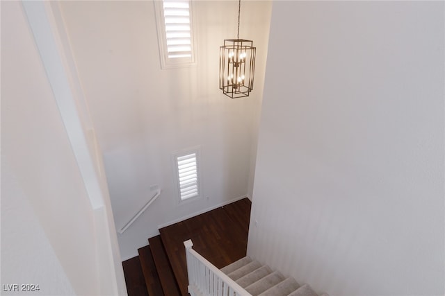 stairway with hardwood / wood-style floors and a notable chandelier