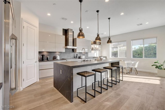 2567 Speyburn Ave, Henderson, NV 89044 - kitchen with wall chimney exhaust hood, modern cabinets, a breakfast bar, decorative backsplash, and white cabinets