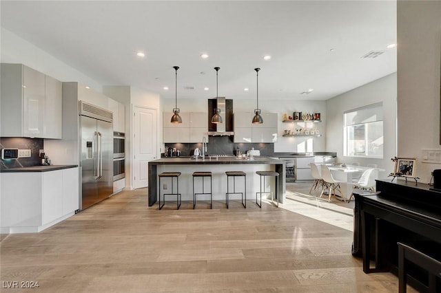 2567 Speyburn Ave, Henderson, NV 89044 - kitchen featuring appliances with stainless steel finishes, wall chimney range hood, dark countertops, a breakfast bar area, and decorative backsplash