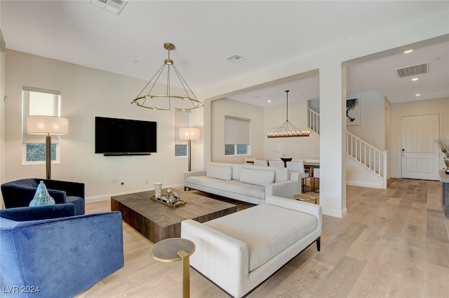 living room with light hardwood / wood-style flooring and an inviting chandelier