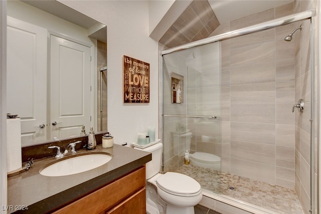 bathroom featuring vanity, toilet, and a shower with shower door