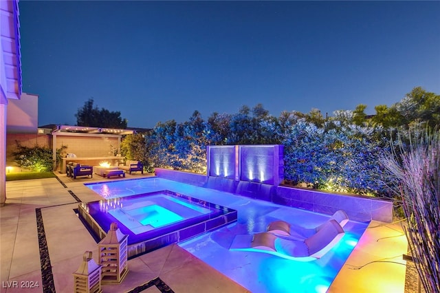 pool at night with an in ground hot tub and a patio