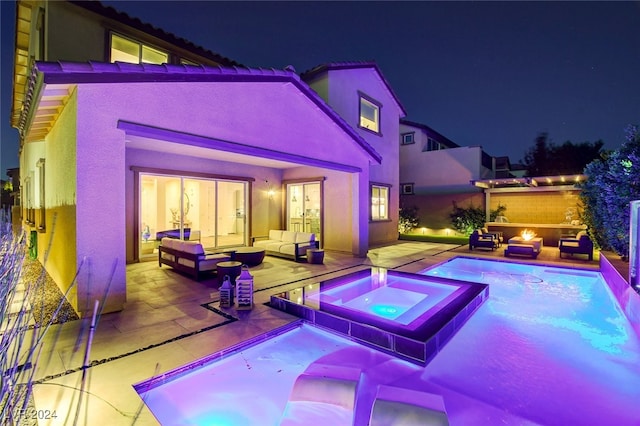 pool at twilight with an in ground hot tub, an outdoor hangout area, and a patio