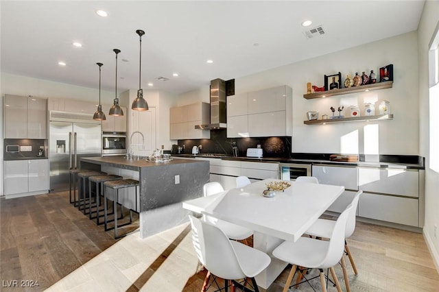2567 Speyburn Ave, Henderson, NV 89044 - kitchen featuring stainless steel appliances, wall chimney range hood, modern cabinets, beverage cooler, and dark countertops