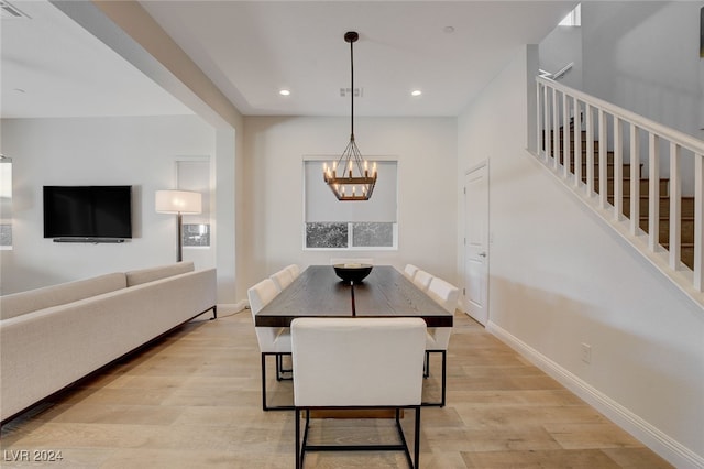 dining area with light hardwood / wood-style floors and an inviting chandelier