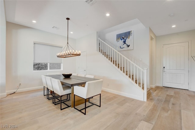 dining room with light hardwood / wood-style floors and an inviting chandelier