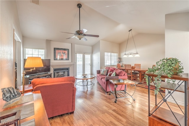 living room featuring ceiling fan, light wood-type flooring, plenty of natural light, and vaulted ceiling