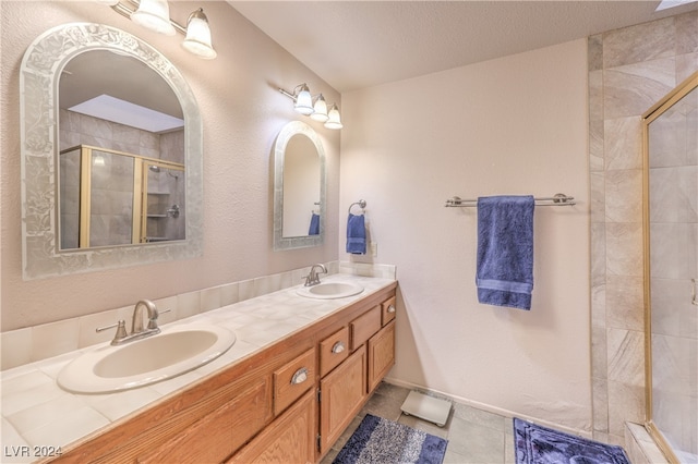 bathroom with a shower with door, vanity, a textured ceiling, and tile patterned flooring