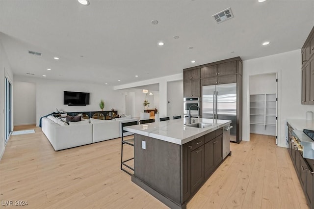 kitchen featuring a center island with sink, light wood-type flooring, sink, and appliances with stainless steel finishes