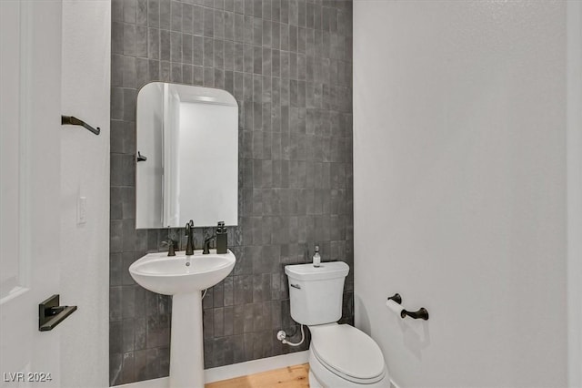 bathroom with hardwood / wood-style flooring, toilet, and tile walls