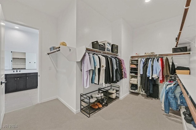 walk in closet with light carpet and sink