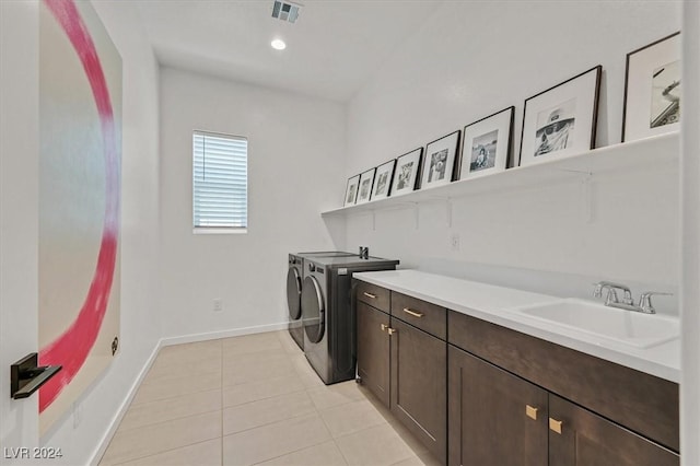 washroom featuring washer and dryer, cabinets, light tile patterned floors, and sink