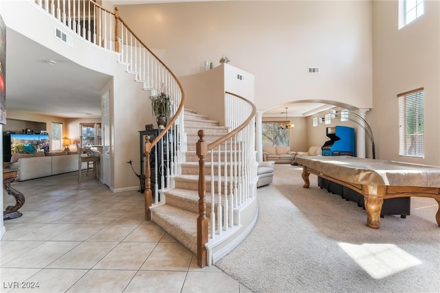 playroom featuring a notable chandelier, a healthy amount of sunlight, a high ceiling, and light tile patterned flooring