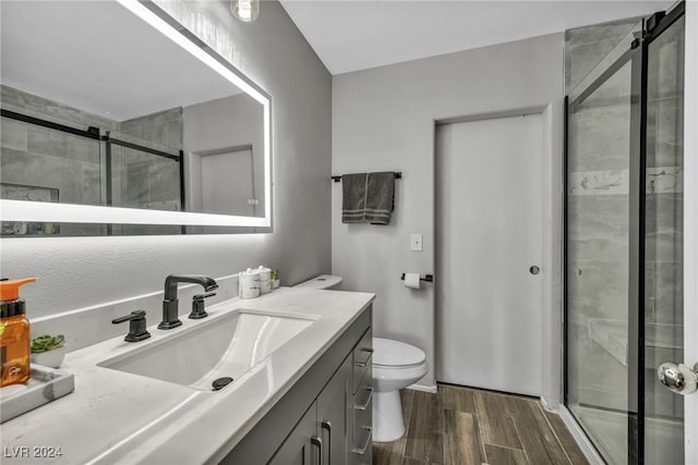 bathroom with vanity, wood-type flooring, toilet, and a shower with shower door