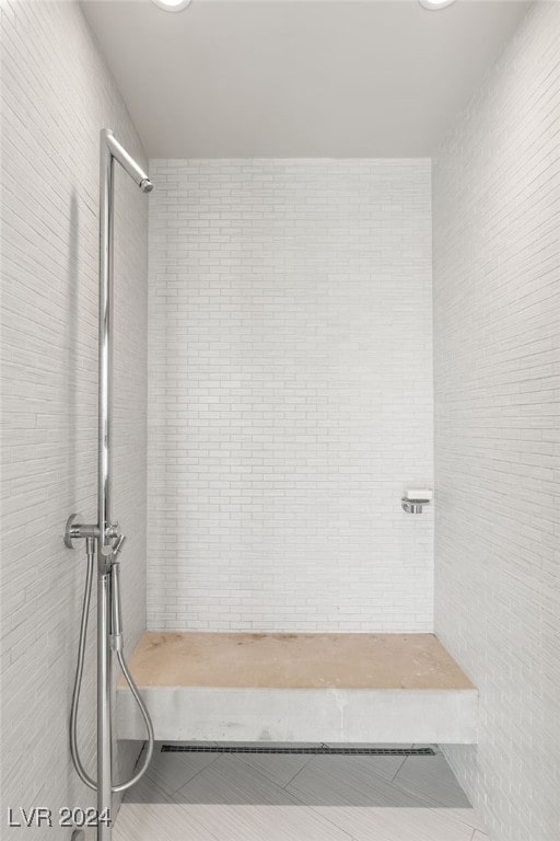 bathroom with a tile shower and tile patterned flooring