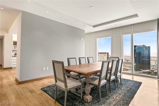 dining area with light hardwood / wood-style floors and a tray ceiling