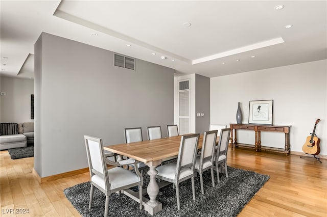 dining area featuring a tray ceiling and light hardwood / wood-style flooring