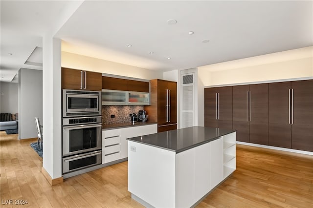 kitchen featuring tasteful backsplash, light wood-type flooring, a center island, white cabinetry, and stainless steel appliances