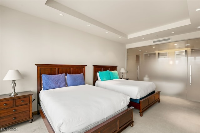 bedroom featuring light carpet and a tray ceiling