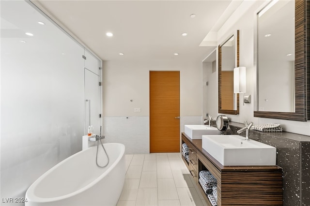 bathroom with vanity, a tub, and tile walls