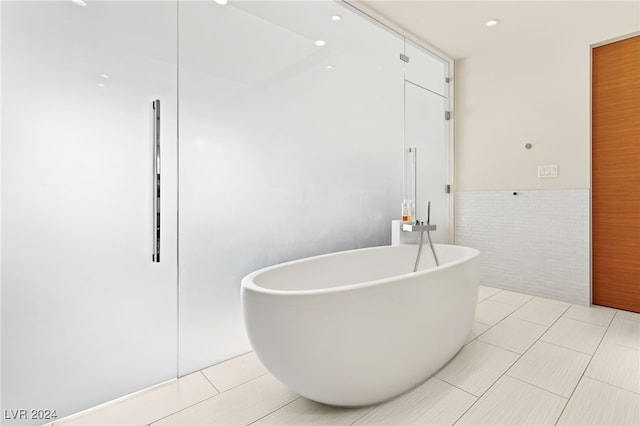 bathroom with a tub, tile patterned floors, and tile walls