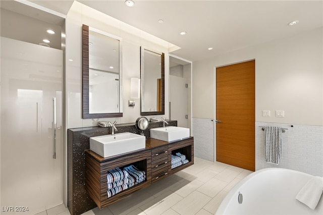 bathroom with tile walls, vanity, a bathtub, and tile patterned floors