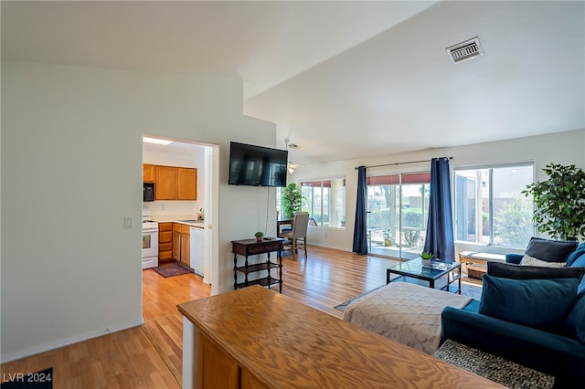 living room with sink, vaulted ceiling, and light wood-type flooring