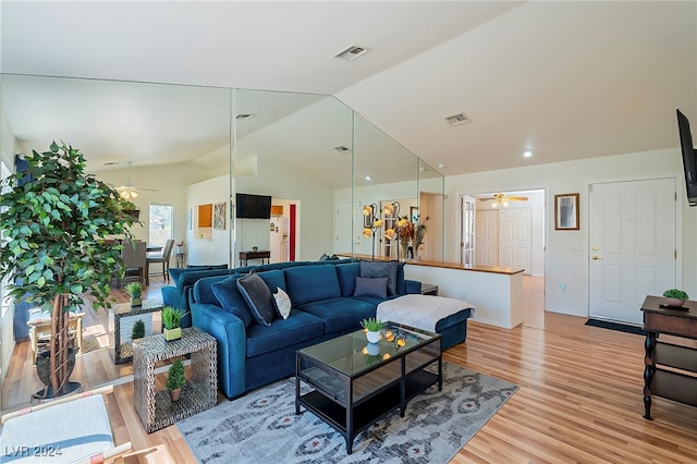 living room with ceiling fan, lofted ceiling, and light hardwood / wood-style flooring