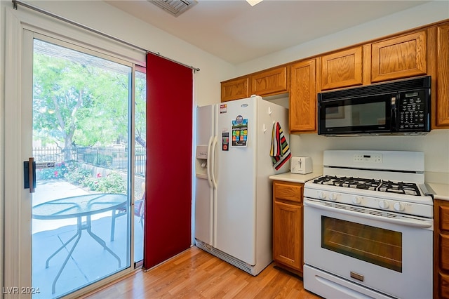 kitchen with light hardwood / wood-style flooring and white appliances