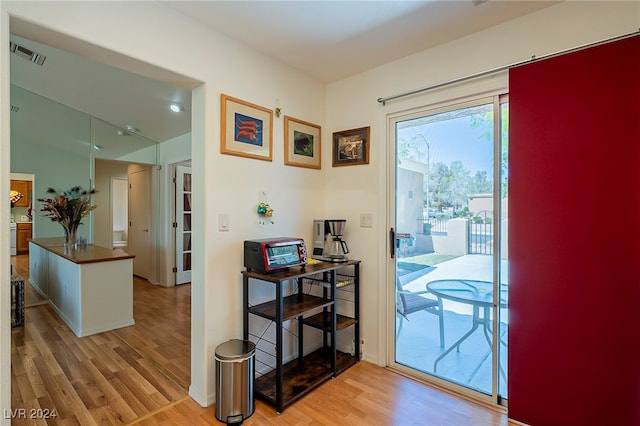 doorway to outside with light hardwood / wood-style flooring and vaulted ceiling