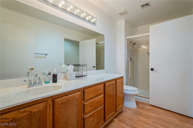 bathroom with toilet, hardwood / wood-style floors, vanity, and a shower with door