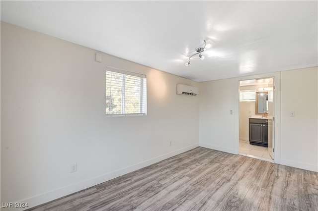 spare room featuring a wall mounted air conditioner and light wood-type flooring