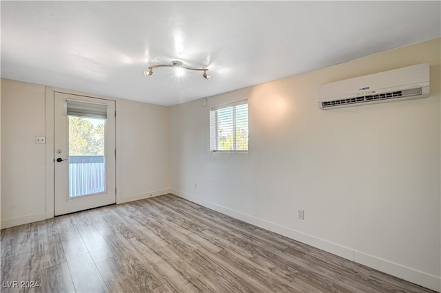 unfurnished room featuring light hardwood / wood-style floors and an AC wall unit