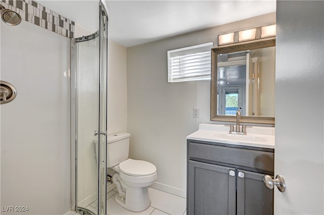 bathroom featuring toilet, a shower with shower door, vanity, and tile patterned flooring