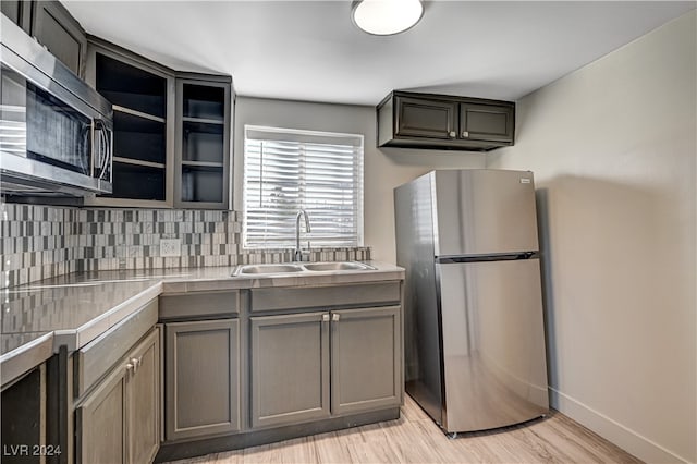 kitchen featuring backsplash, sink, appliances with stainless steel finishes, and light hardwood / wood-style floors